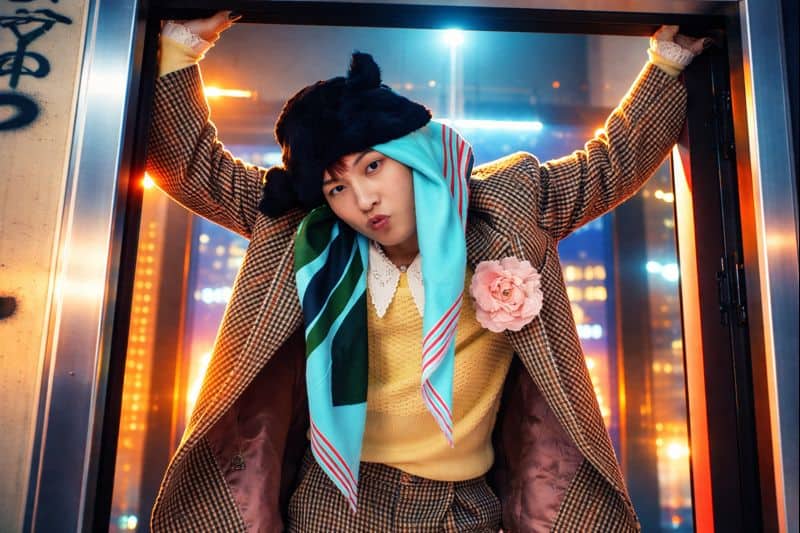 Quirky idol hangs in doorway, neon blue-orange glow.